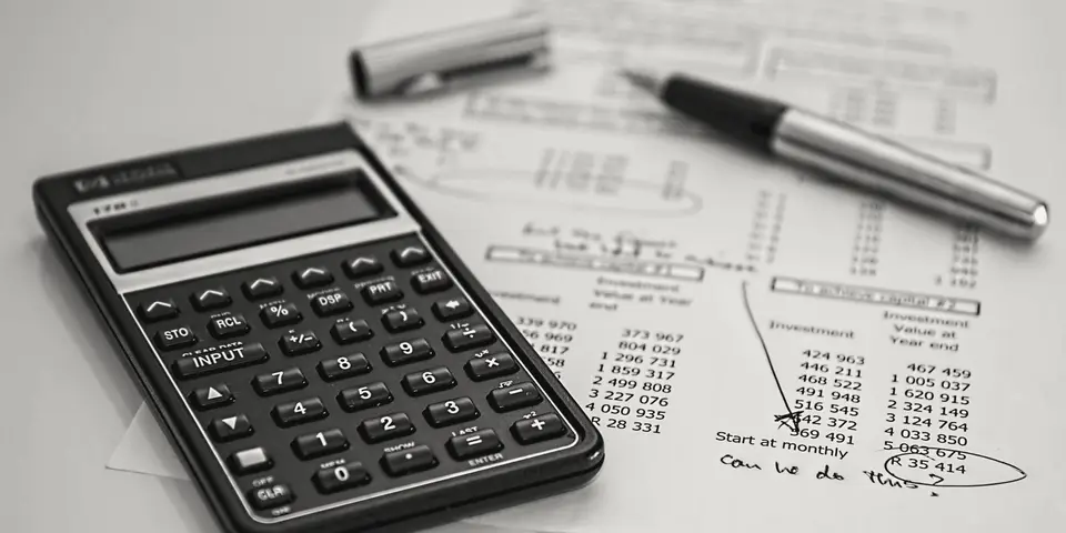 A calculator and pen on a page of handwritten figures