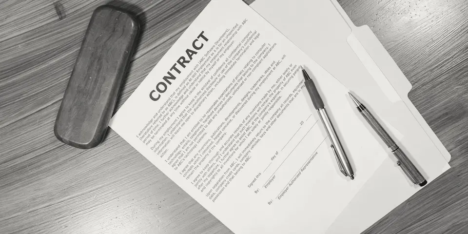 A contract and two pens on a wooden table