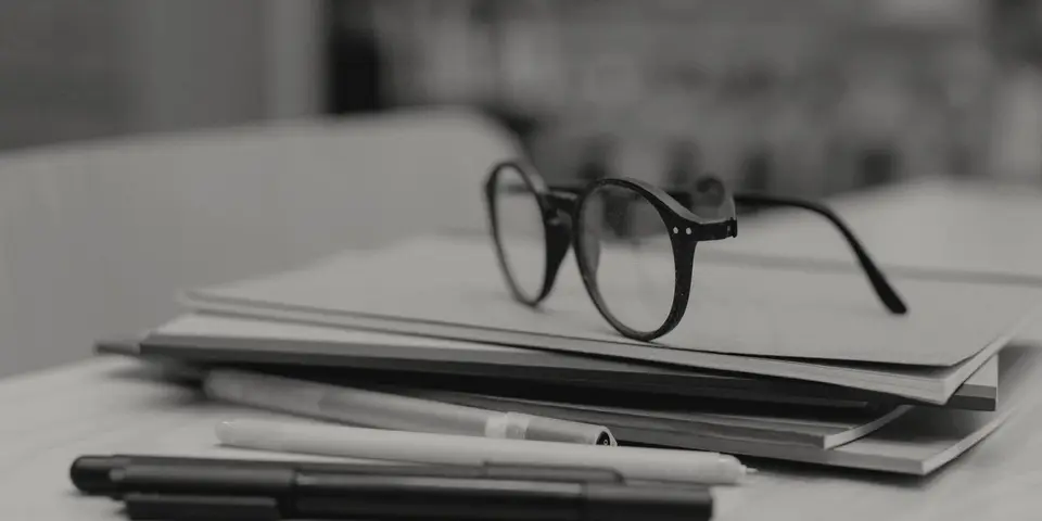 Reading glasses on a stack of notebooks with pens