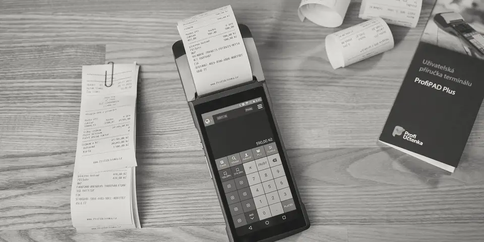 A card payment terminal and printed sales receipts on a desk