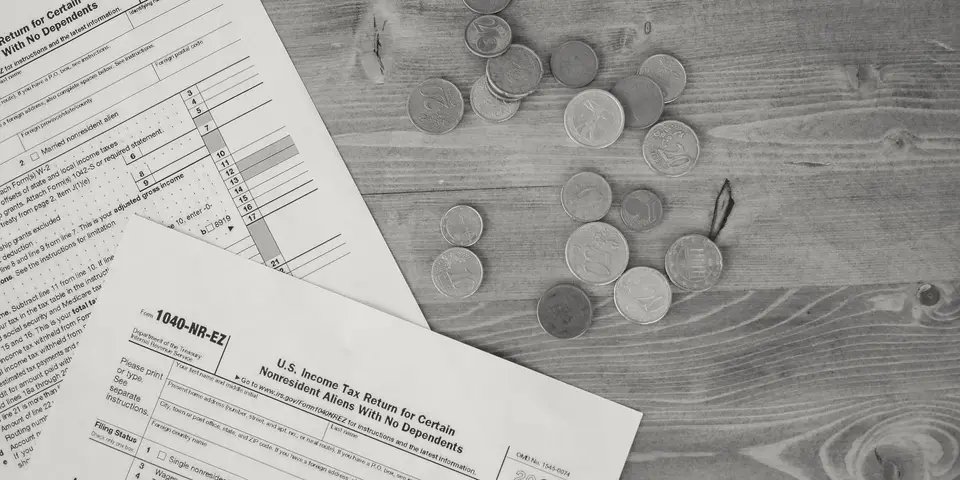 Tax forms and coins spread on a wooden table